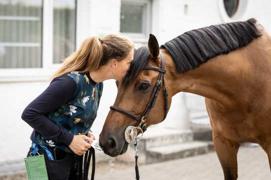 Das Foto zeigt eine Pferdepflegerin bei einem wichtigen To Do der täglichen Zusammenarbeit: die Knuddeleinheit. Foto: Jasmin Metzner