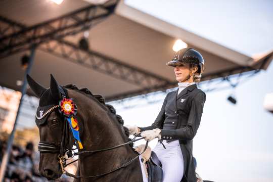 Simone Pearce und Fine Art von Bellin mit einer blau und deutschlandfarbenen Schleife am Kopf beim Einritt zur Siegerehrung