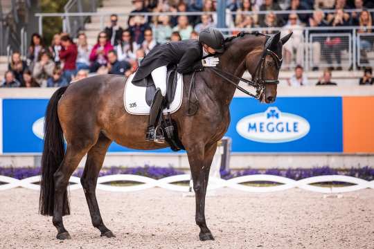 Jessica von Bredow-Werndl in a black tailcoat leans forward in the saddle to hug her mare Dalera and pat her on the neck in front of the packed grandstand in the Dressage Stadium.